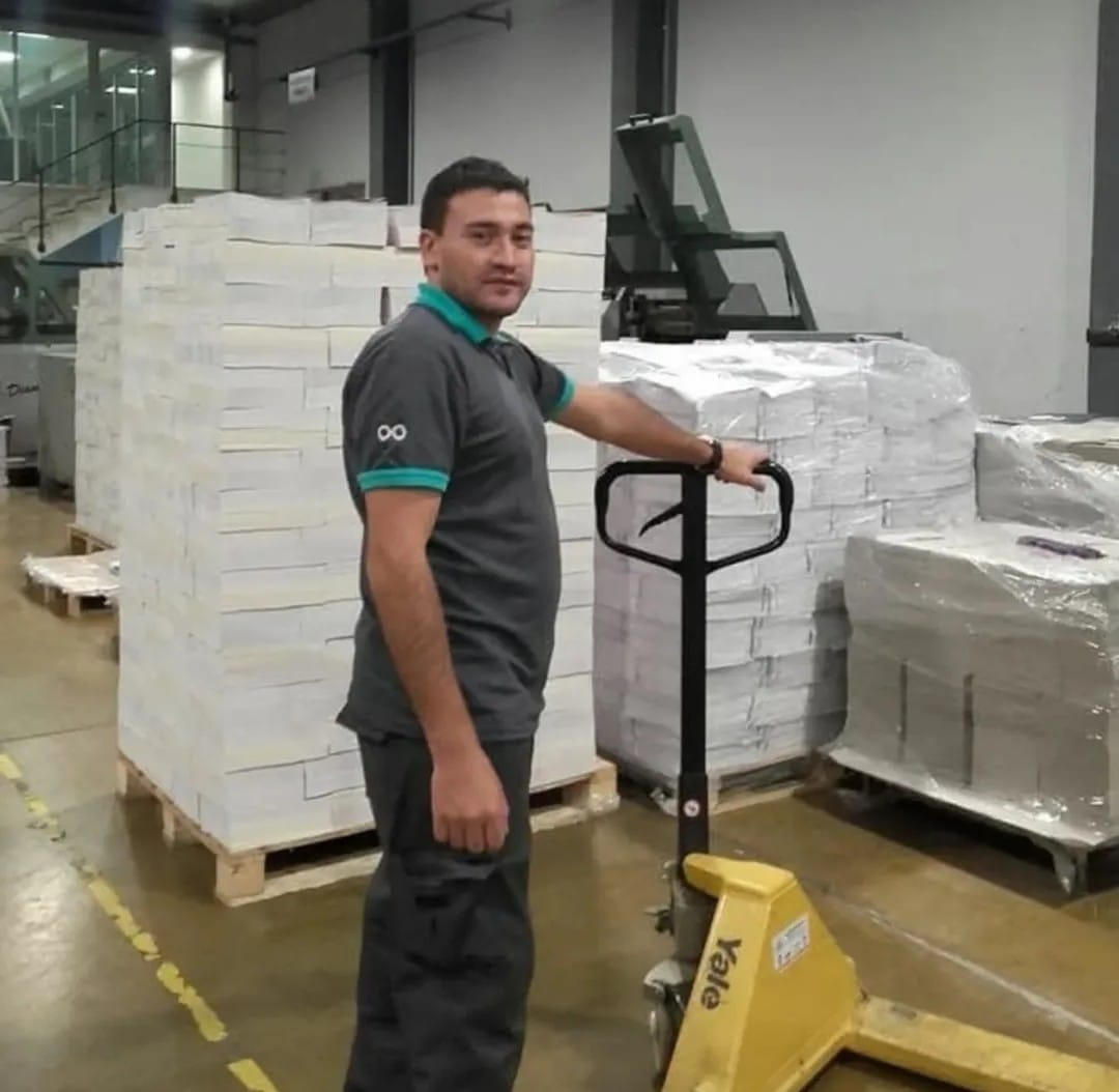 Operario de logística con uniforme gris y detalles turquesa en depósito